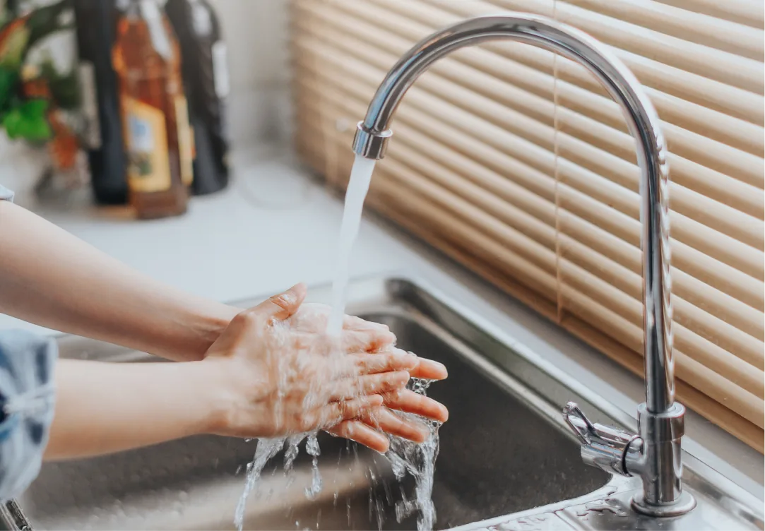 lady washing her hands under a kitchen sink