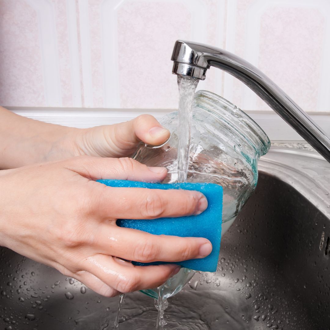 person washing glass jar in kitchen sink person washing glass jar in kitchen sink
