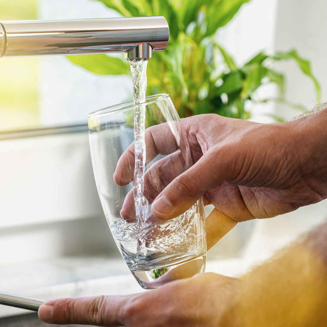 person pouring water into glass from faucet person pouring water into glass from faucet